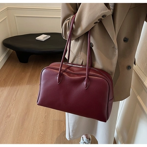 Dettaglio della borsa tote bordeaux in pelle martellata con zip e sottili tracolle lunghe