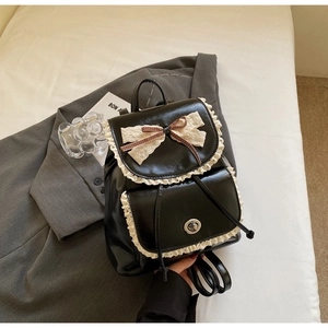 Detail view of black PU leather backpack featuring white lace trim and ribbon bow accents