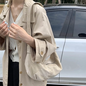 Close-up of minimalist cream crescent shoulder bag with soft matte texture and wide strap