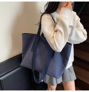 Side view of navy canvas tote bag worn by model showing its large capacity and sleek style