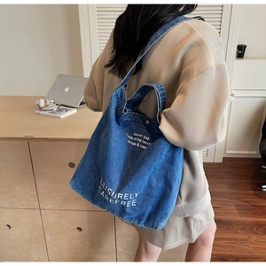 Close-up of vintage blue denim tote bag texture with white artistic letter printing