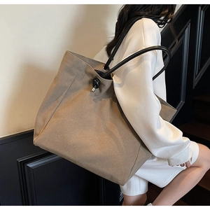 Detail of khaki canvas tote bag with black round handle and decorative knot detail