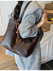 Fashionable dark brown tote bag with vintage texture and beaded charm on model
