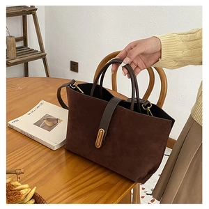 Close-up of dark brown suede bucket bag featuring a vintage golden oval metal buckle