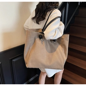 Detail of khaki tote bag with black tubular handles and large ball knot decorative charm