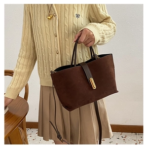 Detail view of coffee brown suede tote bag featuring sleek golden metal hardware clasp