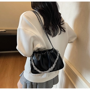 Detail of black pleated cloud bag with shiny leather texture and silver chain strap