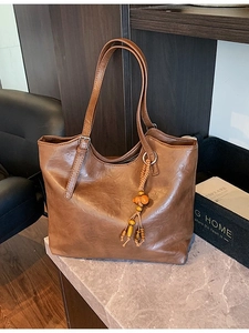 Brown large capacity PU leather tote bag with colorful beaded tassel on a chair