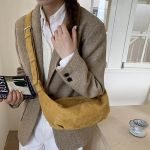 Detail of the mustard yellow suede dumpling bag showing smooth matte texture and wide strap