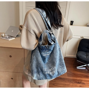 Close-up of washed blue denim tote bag featuring Leisurely Carefree printed text detail