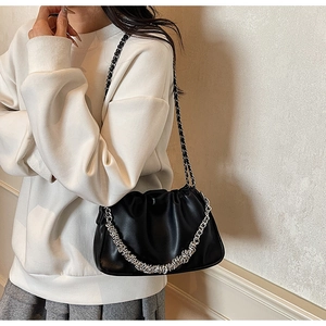 Detail of black pleated cloud bag with dual silver chains and fine leather texture