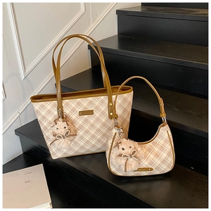 Detail of checkered tote and crescent bag set with plush bunny charms on wooden stairs
