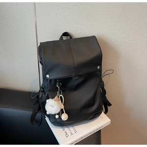 Detail view of water-resistant nylon backpack with silver buckle and plush pompom decor
