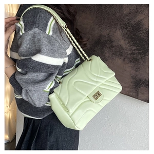 Detail of light green quilted chain bag with wave stitching and gold turn-lock closure