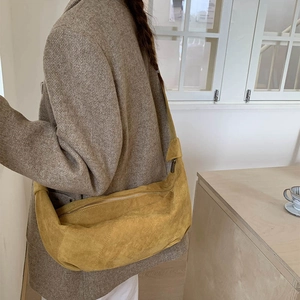 Detail of mustard yellow suede crescent crossbody bag worn with gray tweed blazer