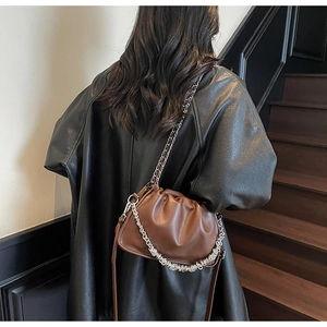 Brown pleated cloud bag with delicate chain strap worn with a black leather jacket