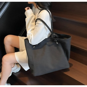 Detail of a black large-capacity tote bag with sleek leather straps and silver hardware