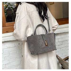 Close-up of matte grey tote bag with elegant gold metal buckle and dual handles