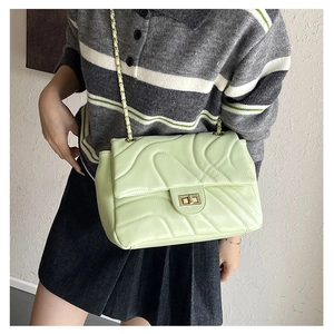 Close-up of mint green quilted crossbody bag with gold chain strap and metal lock