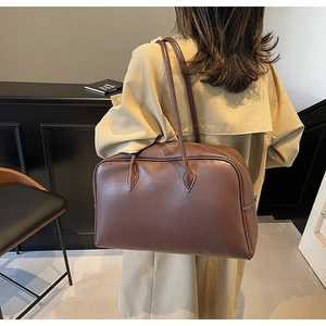 Dettaglio di una borsa tote in pelle marrone scuro abbinata a un trench beige
