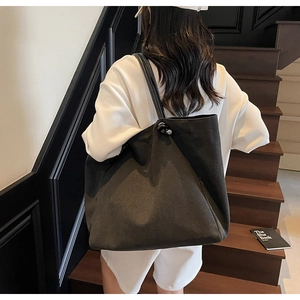Rear view of a minimalist black canvas tote bag with slim leather straps on stairs