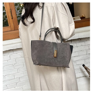 Detail of gray frosted suede tote bag with gold metal lock and leather strap accents