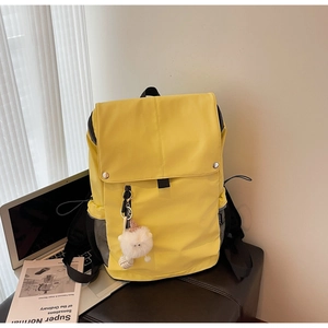 Detail of waterproof nylon backpack showing silver magnetic buckle and plush ball charm