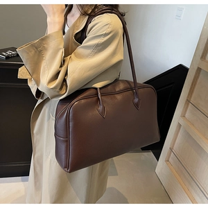 Dettaglio di una grande borsa tote in pelle marrone scuro con texture a grana su una modella