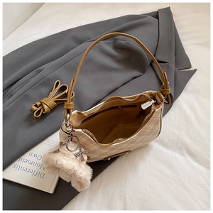 Macro detail of beige plaid hobo bag with teddy bear charm on grey suit blazer