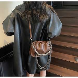 Brown ruched dumpling bag with silver chain and leather strap worn on a black coat