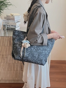 Dunkelgraublaue Shopper-Tasche mit Blumenmuster und Teddybär-Anhänger am Modell