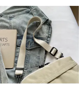 Detail view of the smooth adjustable wide shoulder strap on a cream crossbody bag
