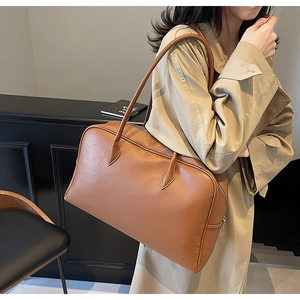 Dettaglio della texture in pelle martellata marrone caramello e tracolla della borsa Boston