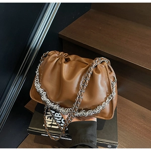 Detail of dark brown pleated cloud bag with chunky silver chain on wooden steps