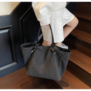 Detail of minimalist black canvas tote bag with leather straps on a wooden staircase