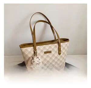 Detail of checkered beige tote bag with a cute white bunny plush charm on a grey coat