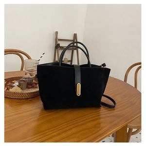 Detail of matte black tote bag with gold oval metal buckle and textured finish