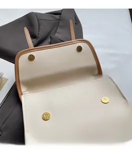 Detail of magnetic snap closures on a cream faux leather tote with brown trim