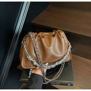 Detailed close-up of brown ruched cloud bag featuring silver metal chain strap