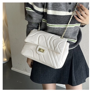 Detail showing the white quilted shoulder bag with gold twist lock and elegant metal chain
