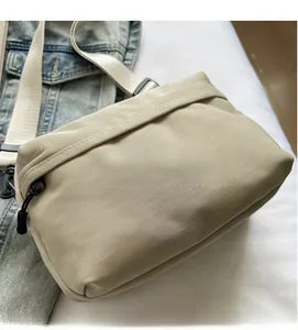 Detail of lightweight beige crossbody bag with smooth texture and adjustable black strap