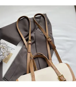 Detail of adjustable brown leather shoulder strap with gold buckle on tote bag