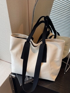 Minimalist large canvas tote bag with black handles displayed in a modern lifestyle setting