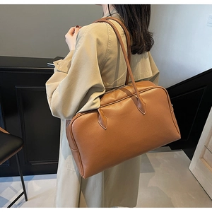 Borsa a spalla in pelle marrone a grana litchi indossata da modella con trench beige