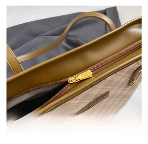 Detailed close-up of golden metal zipper and plaid canvas texture on large tote bag