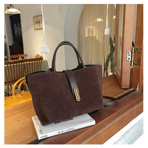 Detail of dark brown suede tote bag with leather handle and golden metallic buckle