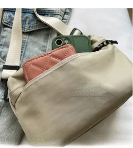 Detail of beige nylon crossbody bag showing inner storage for phone and wallet with zipper