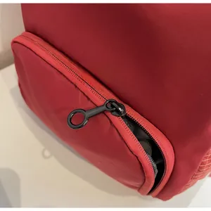 Detailed close-up of smooth black metal zipper on durable red fabric travel bag