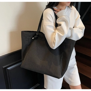 Detail of a large black canvas tote bag with unique knot design and leather shoulder straps