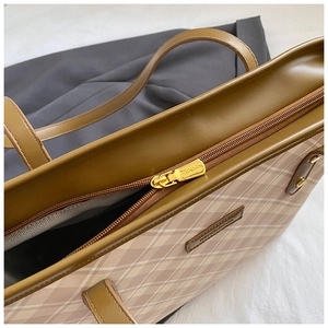 Close-up of olive green leather handle and beige checked fabric with golden zipper